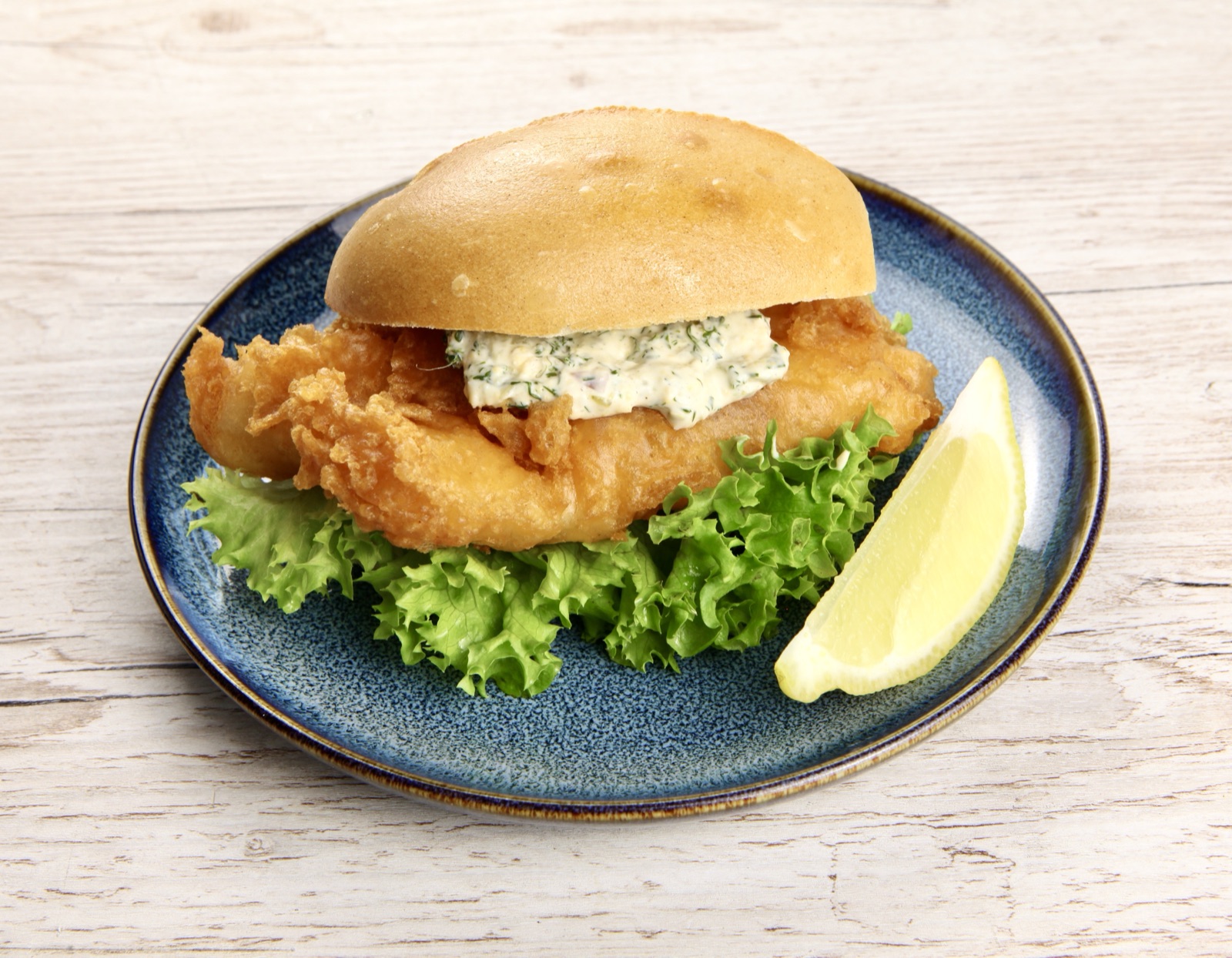 Backfischbrötchen von Morelle — knuspriger Backfisch im Brötchen mit Remoulade und Salat auf blauem Teller